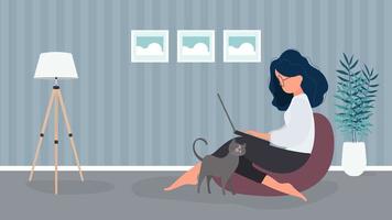 la ragazza si siede su un pouf e lavora al laptop. una donna con un laptop si siede su un grande pouf. il gatto si strofina contro la gamba della ragazza. il concetto di lavoro confortevole in ufficio oa casa. vettore. vettore