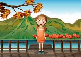 Una giovane ragazza in piedi in mezzo al ponte di legno vettore