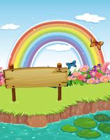 Un&#39;insegna di legno vuota alla riva e un arcobaleno nel cielo vettore