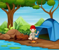 boy scout seduto al campeggio vettore