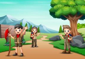 scena con molti bambini in uniforme da scout che fanno un'escursione nel parco vettore