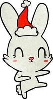 simpatico cartone animato strutturato di un coniglio che balla con il cappello di Babbo Natale vettore