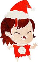 cartone animato retrò di una ragazza vampiro che ride che indossa il cappello di Babbo Natale vettore