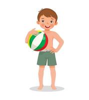 felice ragazzino carino con costume da bagno che tiene pallone da spiaggia gonfiabile con la mano sulla vita posa divertendosi in estate vettore